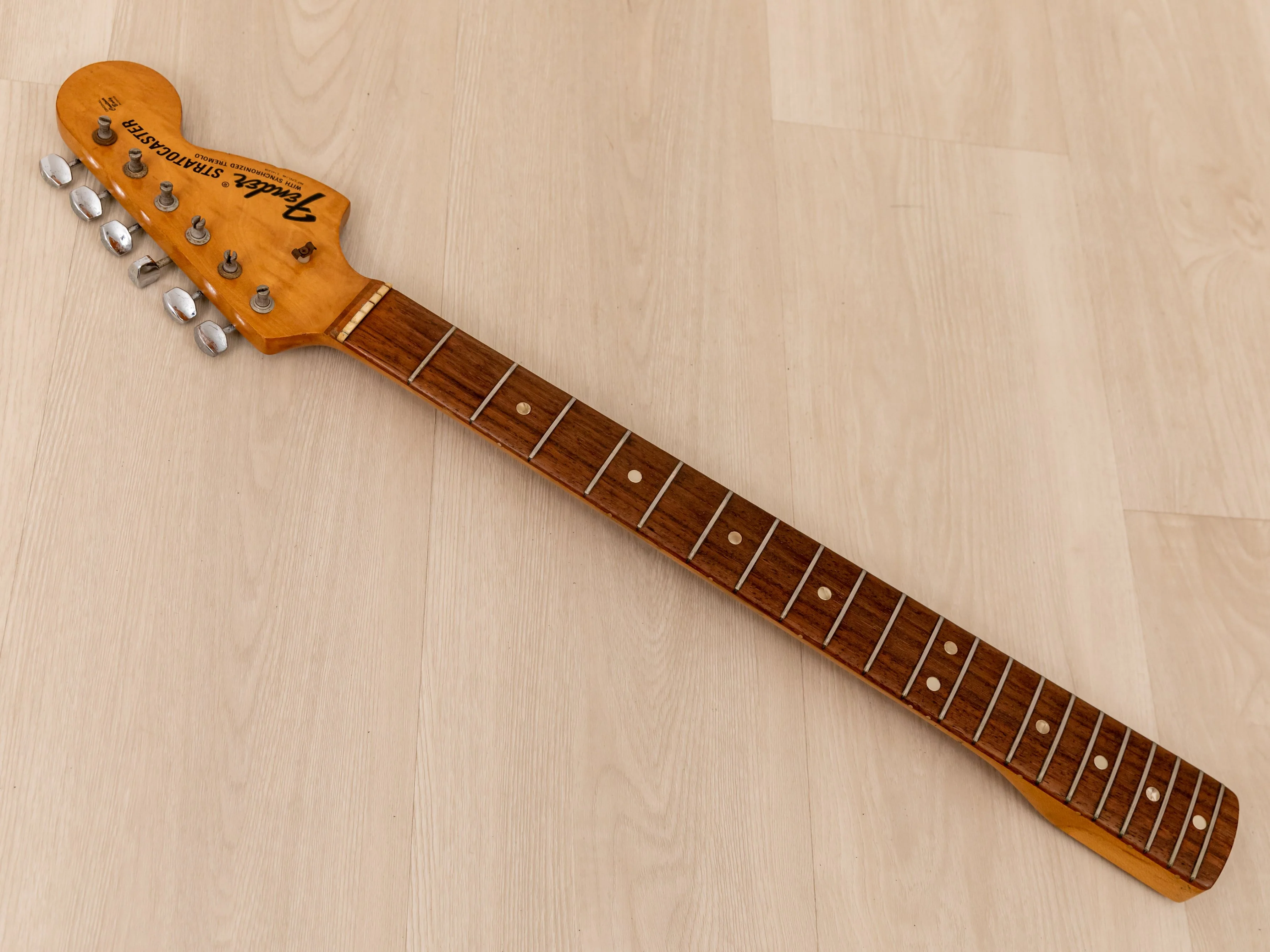 An image of the neck of a guitar. It has frets and the headstock, but is stringless.